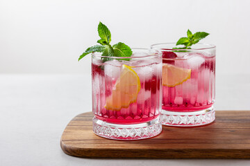 Raspberry cocktail with ice in a glass on a light background