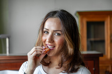 portrait of young beautiful woman is eating an orange in her house