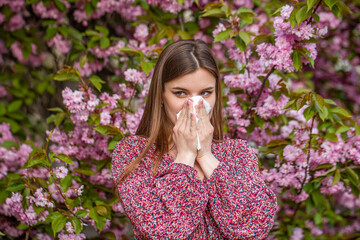 Girl suffering from seasonal pollen allergy. Symptoms of cold or allergy. Sneezing woman nose wiper...