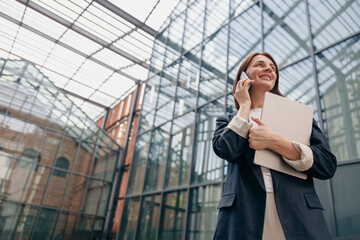 Confident Businesswoman talking on the phone while holding documents in a modern office setting
