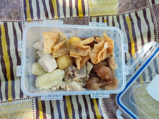 An appetizing close-up of assorted dim sum in a plastic container, featuring a variety of steamed...