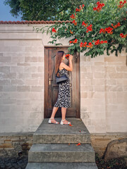 Young woman enjoys a beautiful summer day in vacation standing at the threshold of a door smelling...