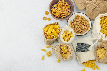 Pasta. Various kinds of uncooked pasta and noodles over light stone background. Traditional Italian