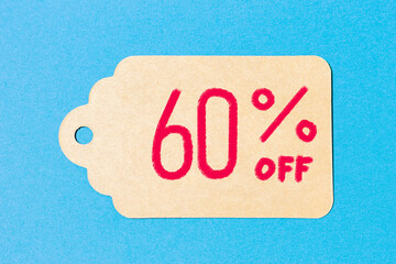 A cardboard label with handwritten text  on flat blue background. 60% off.