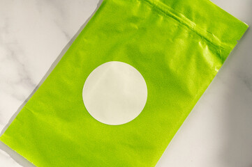 Round white sticker on green poly mailer envelope.