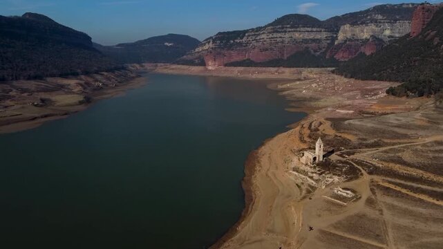 Aerial view os Sau water reservoir in Catalonia with old church with low water levels during drought. Concept of climate change and water crisis
