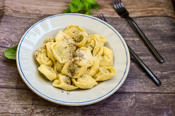 Home made vegetarian  italian   Tortellini with pesto genovese filled with   spinach   and parmesan cheese, decorated with fresh basil