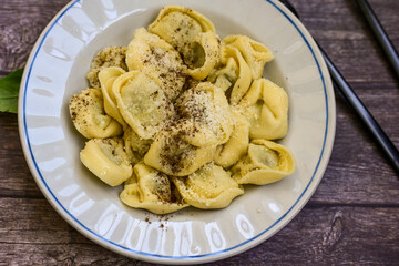 Home made vegetarian  italian   Tortellini with pesto genovese filled with   spinach   and parmesan cheese, decorated with fresh basil