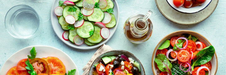 Fresh vegetarian salads panorama, overhead flat lay shot of an assortment. Variety of plates and bowls with green vegetables. Healthy food, with olive oil