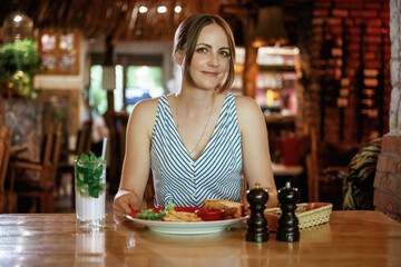 Front view. Woman is in the restaurant with food and drink