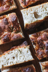 Detailed close-up of sliced focaccia bread pieces on a wooden surface, showcasing the bread's airy...