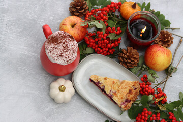 Autumn still life with a cup of hot coffee, blueberry pie, candle, pumpkins and rowan berries. Sweet homemade seasonal pie on a table. 