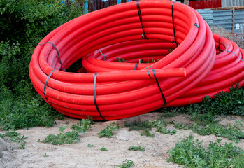 Large red coiled pipes placed on the ground outdoors.