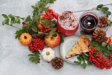 Piece of blueberry pie on a plate with autumn decorations, candle and red flowers. Light grey background with copy space. Cozy autumn food. 