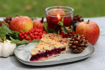 Autumn still life with a cup of hot coffee, blueberry pie, candle, pumpkins and rowan berries. Sweet homemade seasonal pie on a table. 