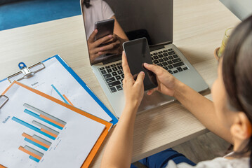 High angle view of woman using cellphone next to laptop