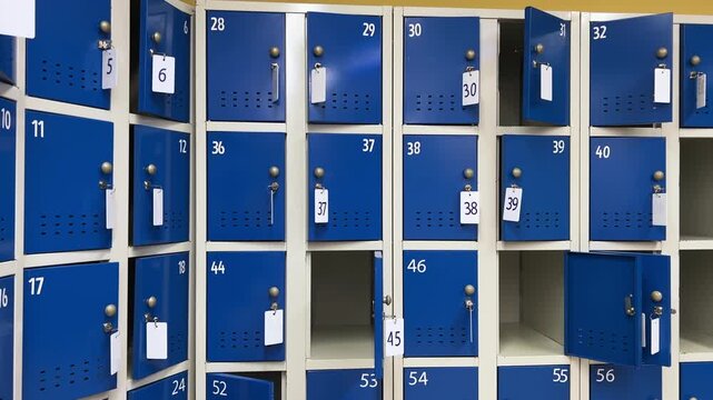Straight-on view: Rows of blue metal lockers with combination locks in a public facility hallway. Personal storage units in an airport, gym, or school setting