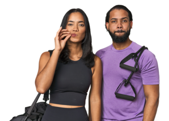 Young Latino couple ready for gym training with fingers on lips keeping a secret.