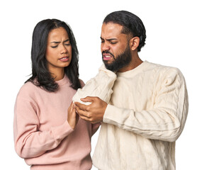 Fototapeta premium Young Latino couple in studio massaging elbow, suffering after a bad movement.