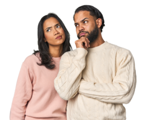 Young Latino couple in studio thinking and looking up, being reflective, contemplating, having a fantasy.