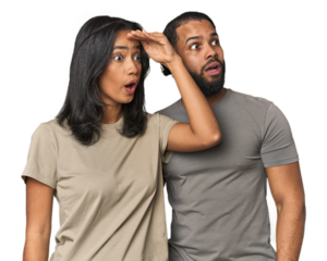 Young Latino couple in studio looking far away keeping hand on forehead.