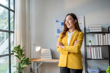 Young asian businesswoman smiling and posing with arms crossed in modern office