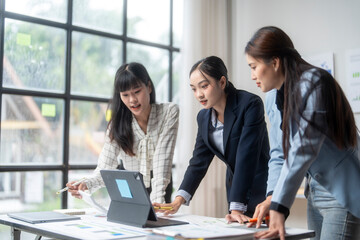 Businesswomen team working on project using tablet analyzing financial documents in office