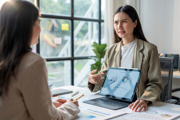 Businesswomen having disagreement about financial chart on tablet in office