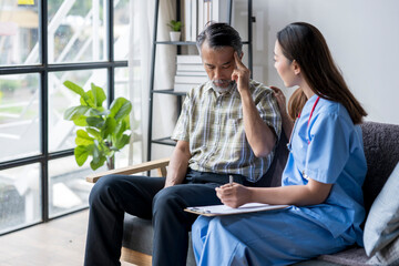 Nurse comforting senior man having headache at home during medical visit