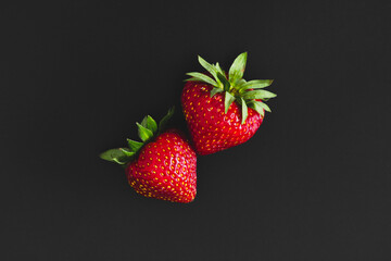 Strawberries isolated on black background. Ripe juicy strawberries. Minimal berries concept. Flat lay, top view, copy space
