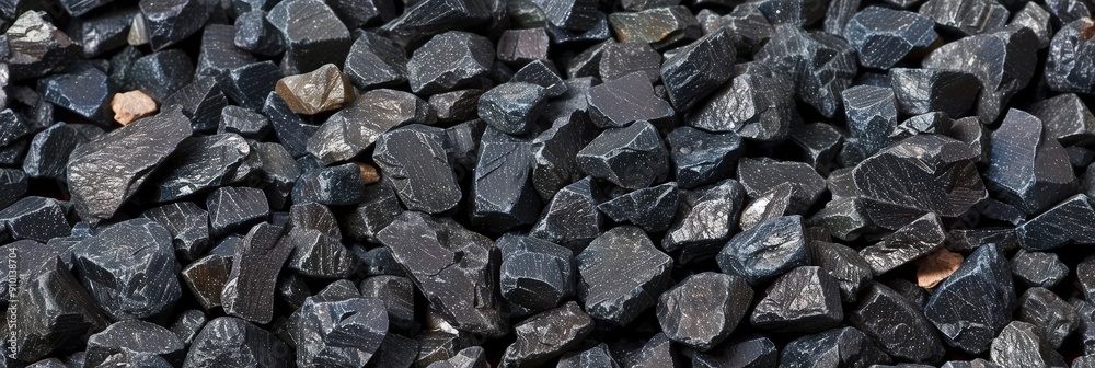 Poster Various sizes of black crushed stone aggregate form a textured surface, commonly used in construction and landscaping projects under bright sunlight