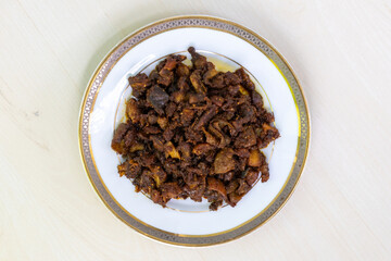 Delicious Bangladeshi food gorur bot bhaja or gorur vuri bhuna in a white plate on wooden background. Beef Bhuri Vaja is a popular Bengali dish made from beef tripe.