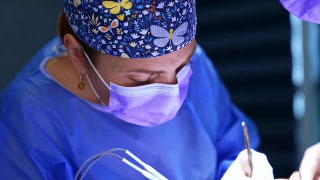 Caucasian female surgeon using medical tools performing operation. Top view on the professional operating thyroid. Close up.