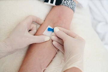Healthcare Professional Placing Bandage on Patient's Arm After IV Insertion in Hospital Room