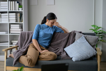 Young Woman Sitting on Couch Feeling Stressed and Overwhelmed in Modern Living Room