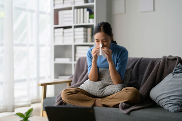 Young Woman Sitting on Sofa Blowing Nose with Tissue in Modern Living Room