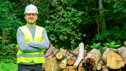 Portrait man forestry worker in protective workwear in front of wood lumber cut tree. Male forestry...