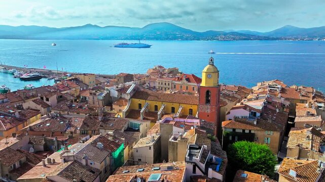 Aerial view of Saint-Tropez's picturesque harbour, a popular sailing and luxury yacht destination. Saint-Tropez colourful houses, church tower on the French Riviera, stone defensive tower in France.