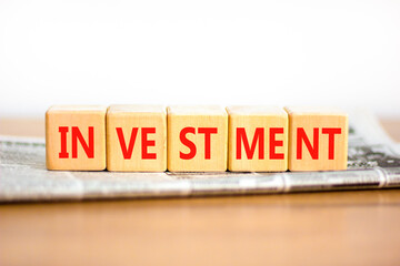 Investment symbol. Concept word Investment on beautiful wooden blocks. Beautiful wooden table white background. Newspaper. Business investment concept. Copy space.