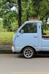 A light blue small truck park on the side of the road