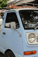 A light blue small truck park on the side of the road