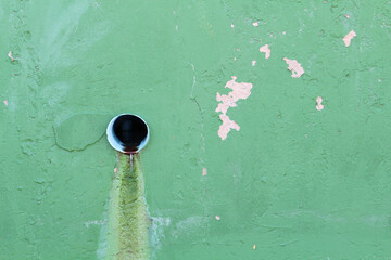 A sewer on the green concrete wall
