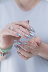 Female hand with long nails and a lilac and green nude nail polish