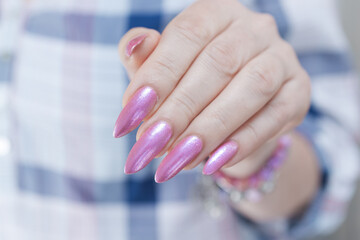 Woman's hands with long nails and a light pink color nail polish