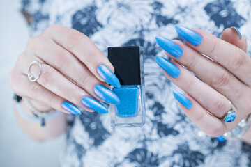 Woman's beautiful hand with long nails and bright blue manicure