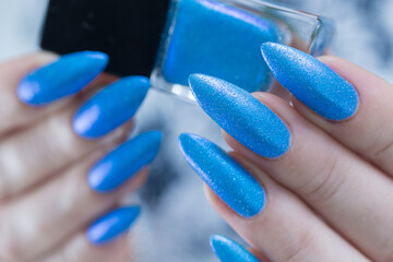 Woman's beautiful hand with long nails and bright blue manicure