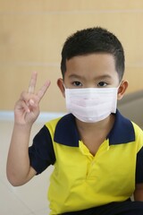 An Asian boy about five years old wearing a mask for prevent respiratory diseases.