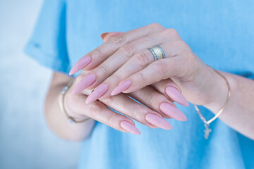 Woman's hands with long nails and a light pink color nail polish