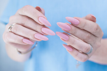 Woman's hands with long nails and a light pink color nail polish