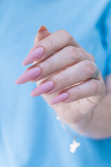 Woman's hands with long nails and a light pink color nail polish
